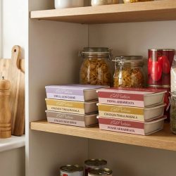 Shelf of high-protein ready meals in a kitchen cupboard
