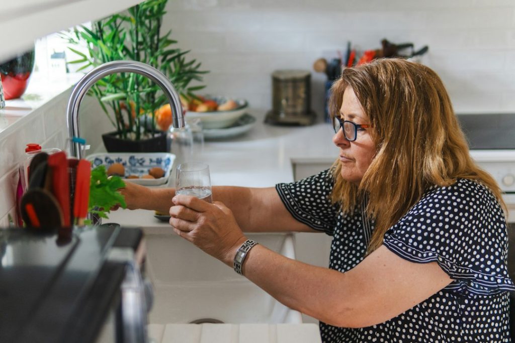 Woman filling a glass of water at the kitchen tap