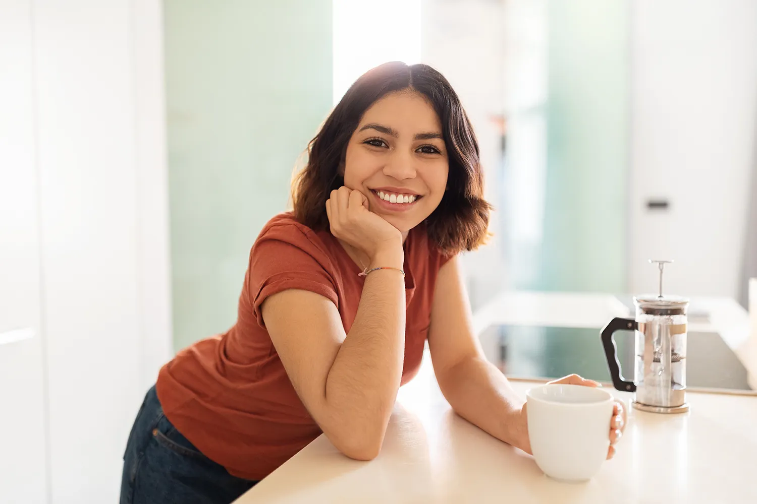 Smiling woman leaning on a kitchen counter with a mug